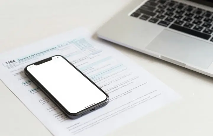 Person sending an IRS tax form as a fax from a phone on a desk